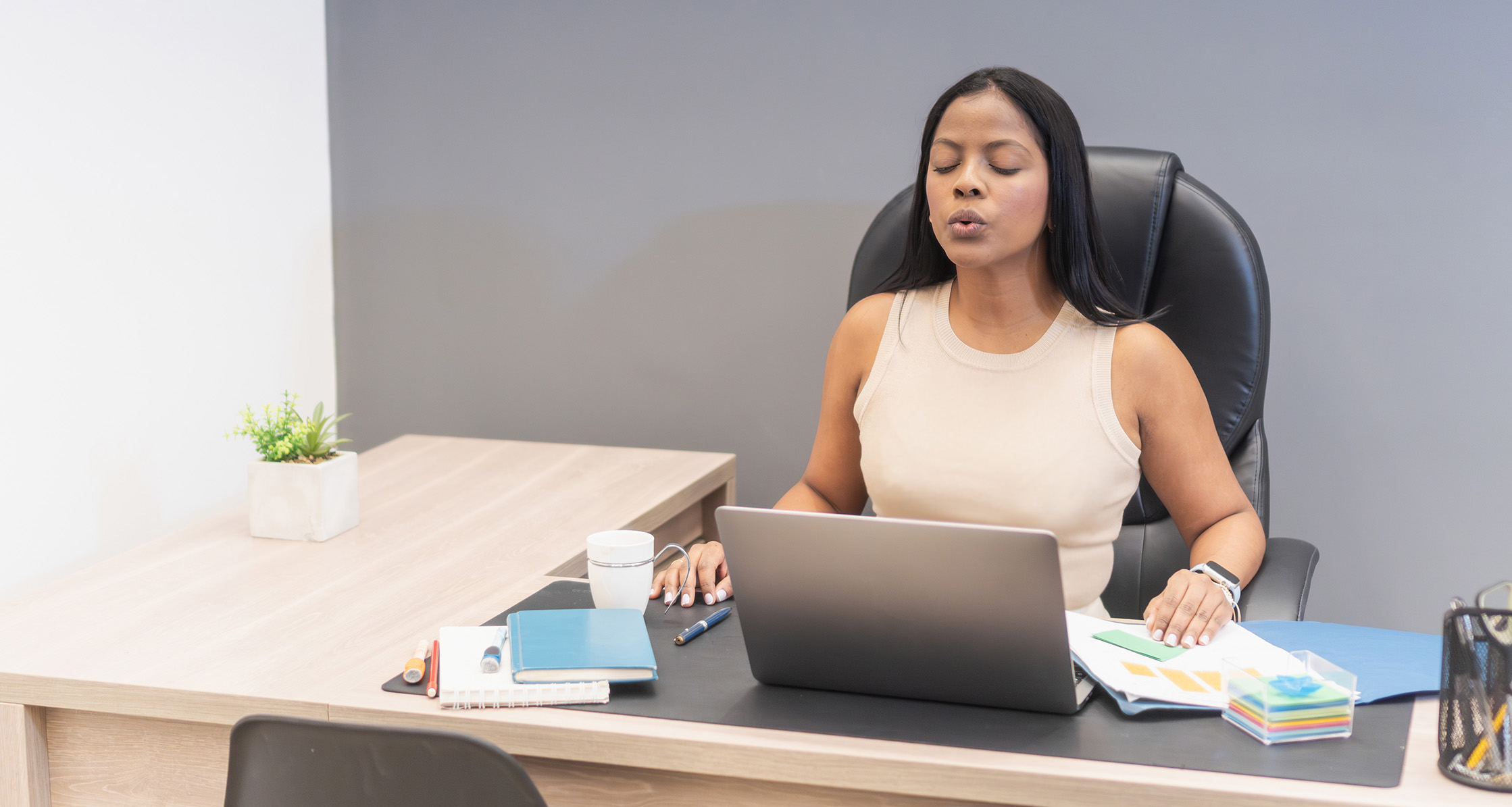 Woman does breathwork at desk.