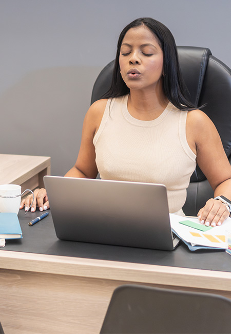 Woman does breathwork at desk.