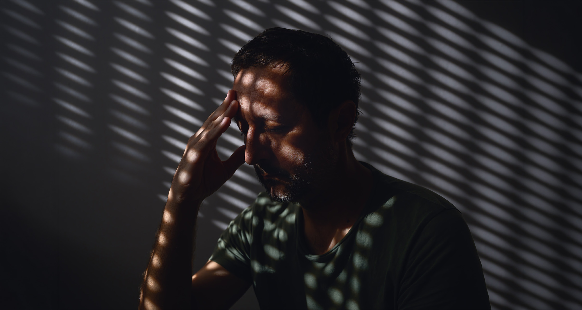 Person in room with blinds closed, avoids light outside.