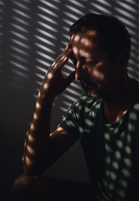 Person in room with blinds closed, avoids light outside.