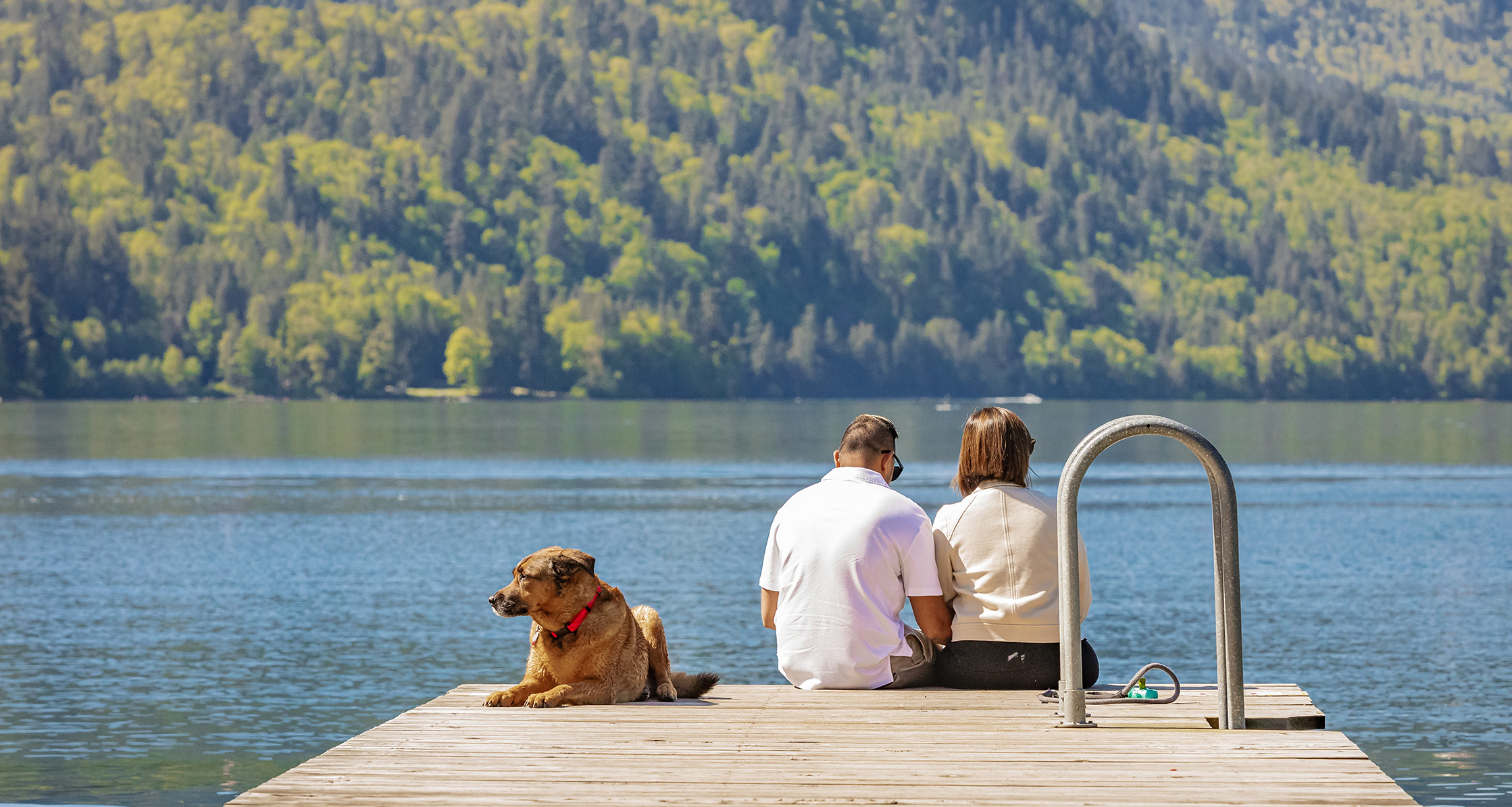 Retired couple sitting together on a dock by a lake.
