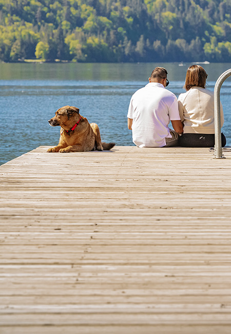 Retired couple sitting together on a dock by a lake.