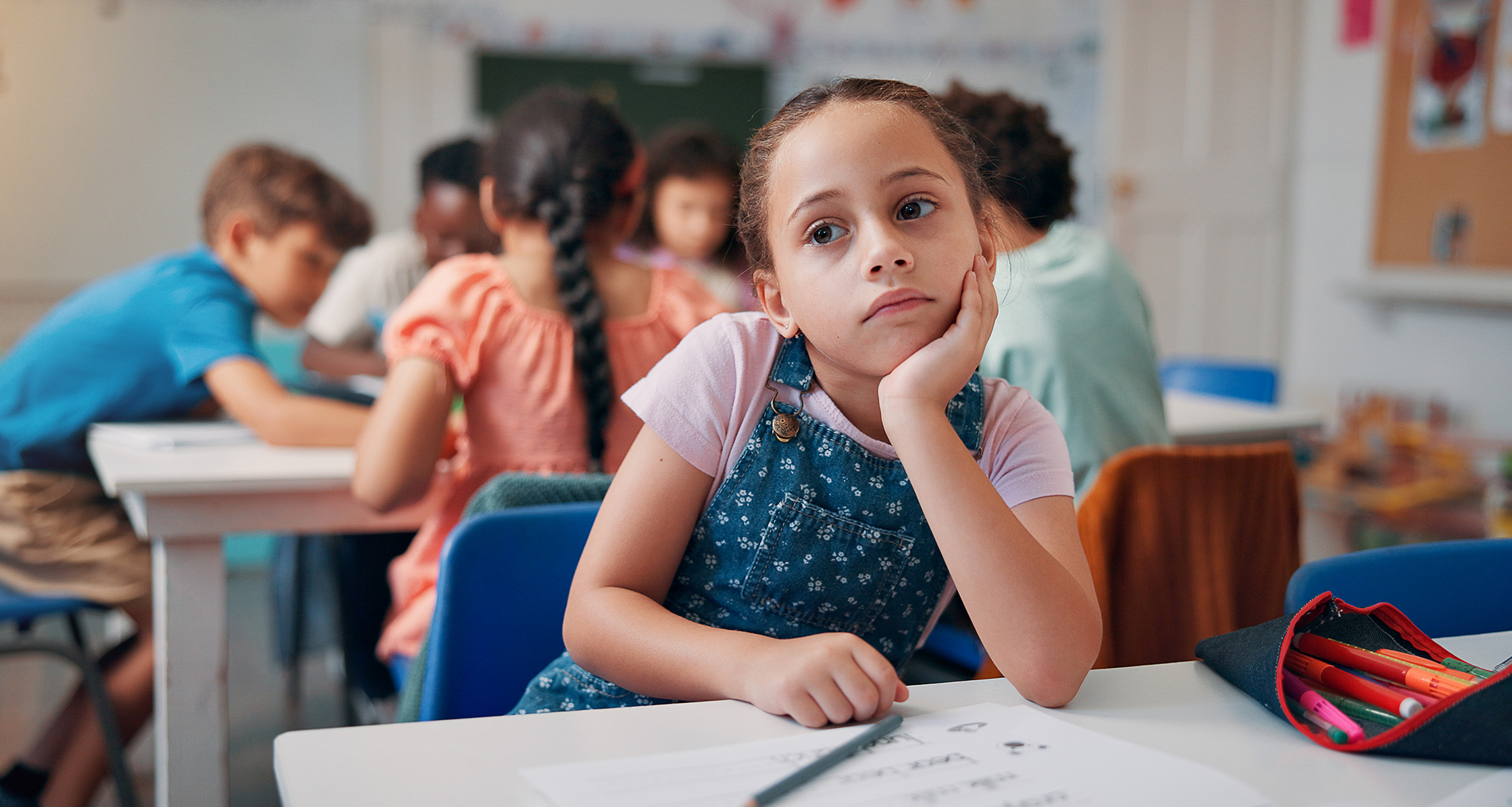 Student in classroom appears to be daydreaming.