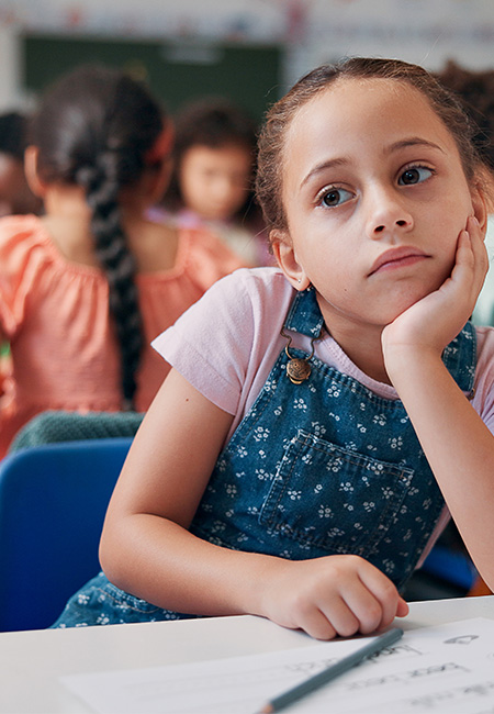 Student in classroom appears to be daydreaming.