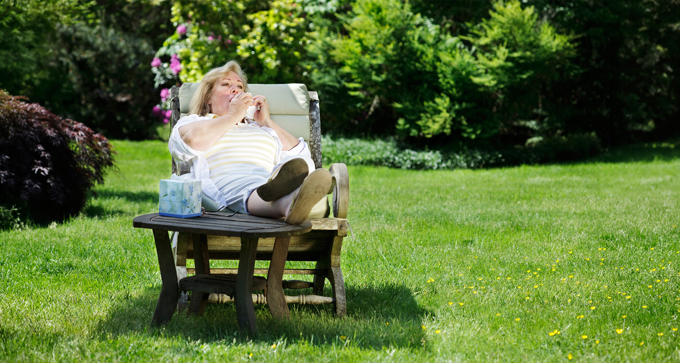 A woman relaxing in her backyard, about to sneeze.