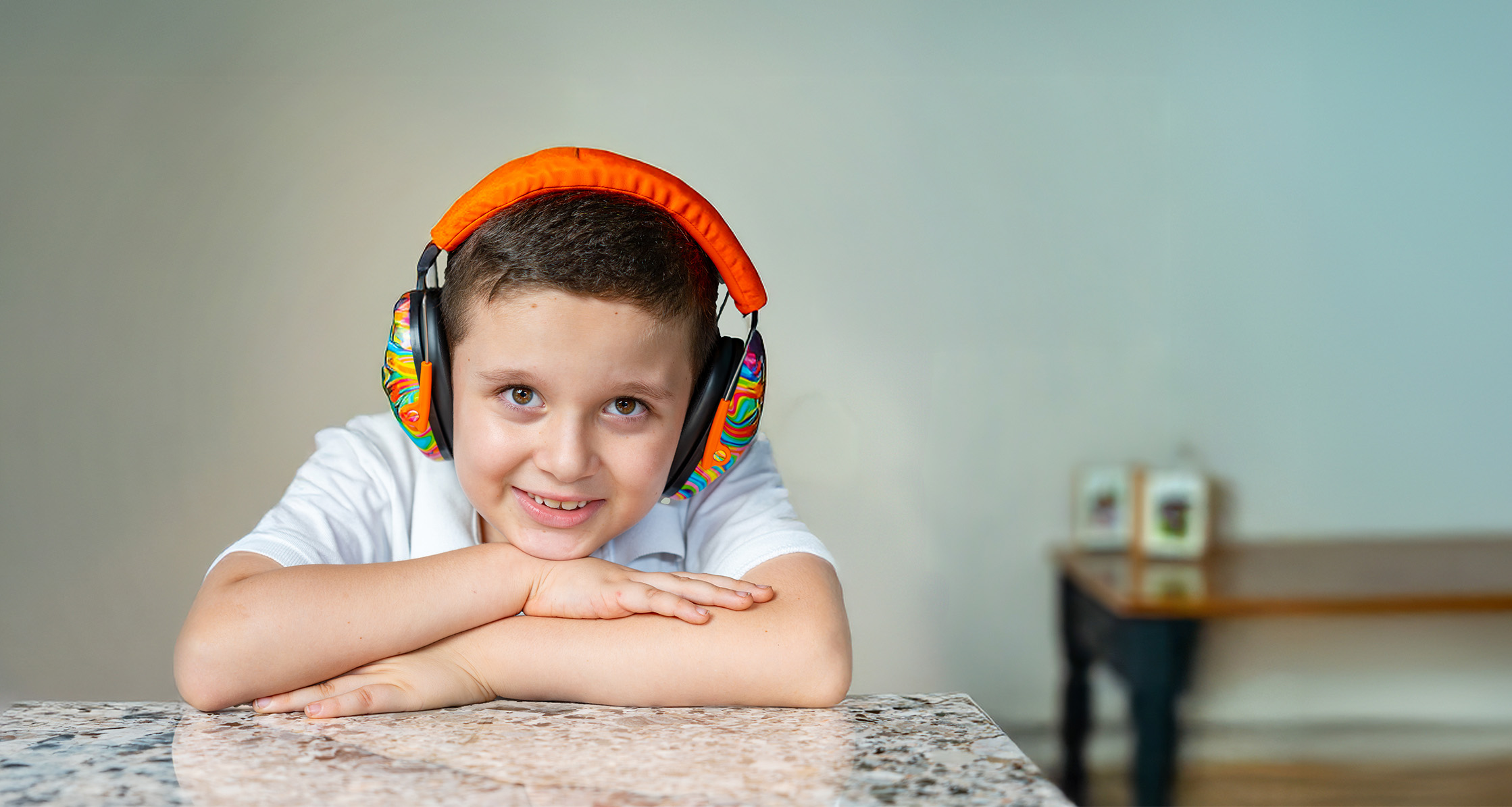 Autistic boy smiling with noise-canceling headphones for sensory comfort.