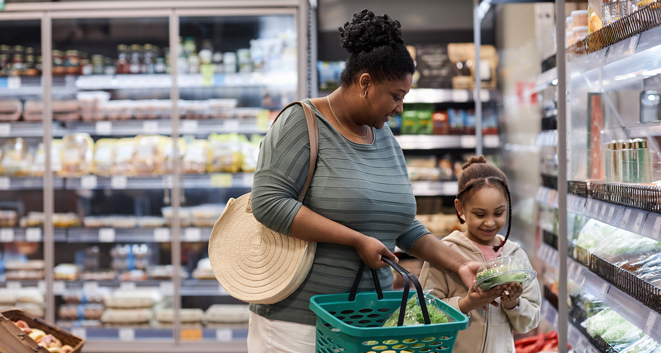 Mother shopping with daughter buying vegetables.