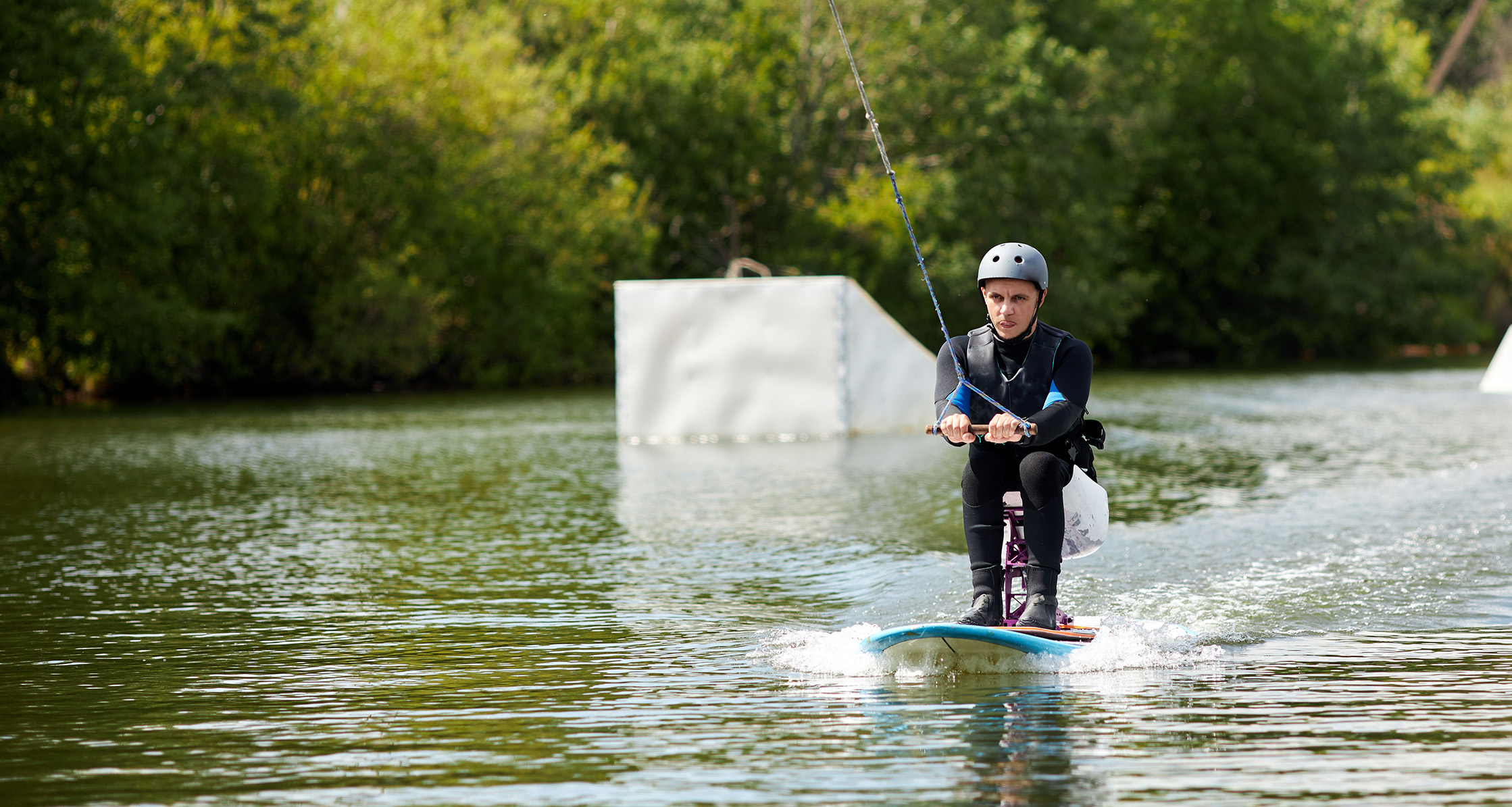 Person using adaptive wakeboard equipment on lake.