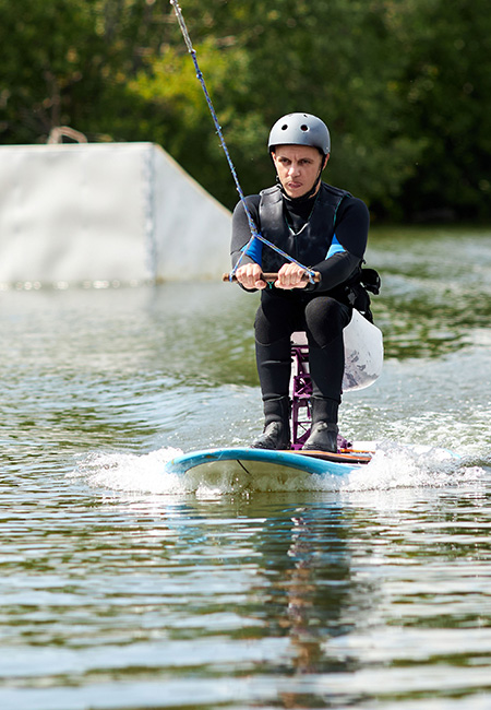 Person using adaptive wakeboard equipment on lake.