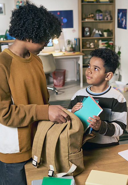 Sibling helps brother pack for school.