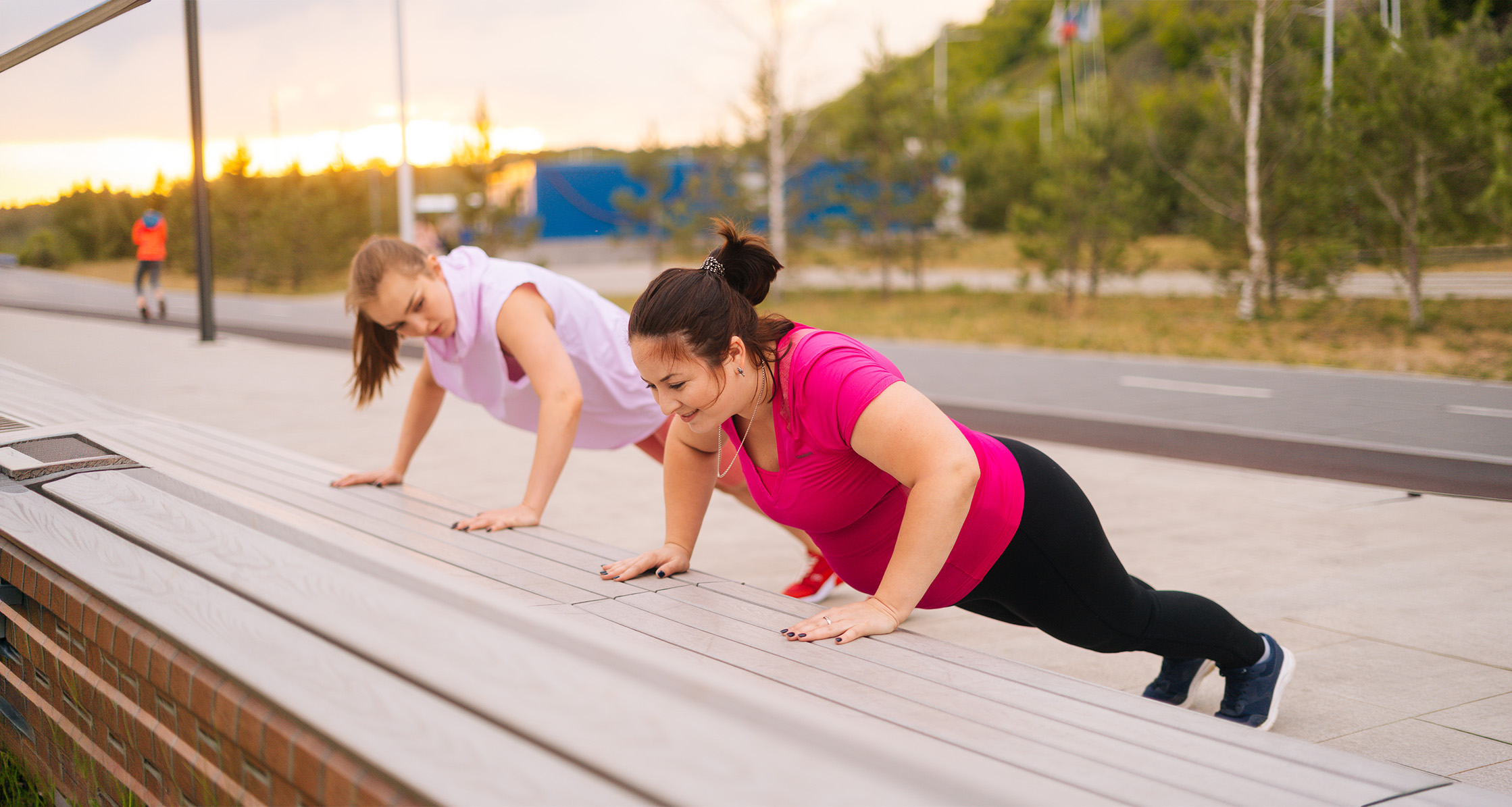 Two women performing incline push-ups outdoors.